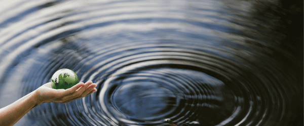 water with drip and hand holding a globe